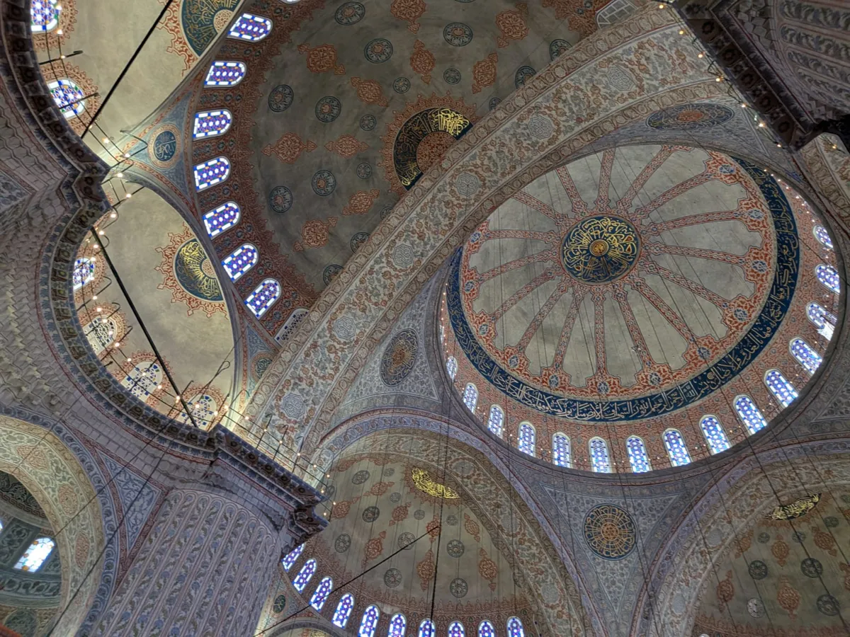 Looking up at the painted domes and stained-glass windows inside the Blue Mosque