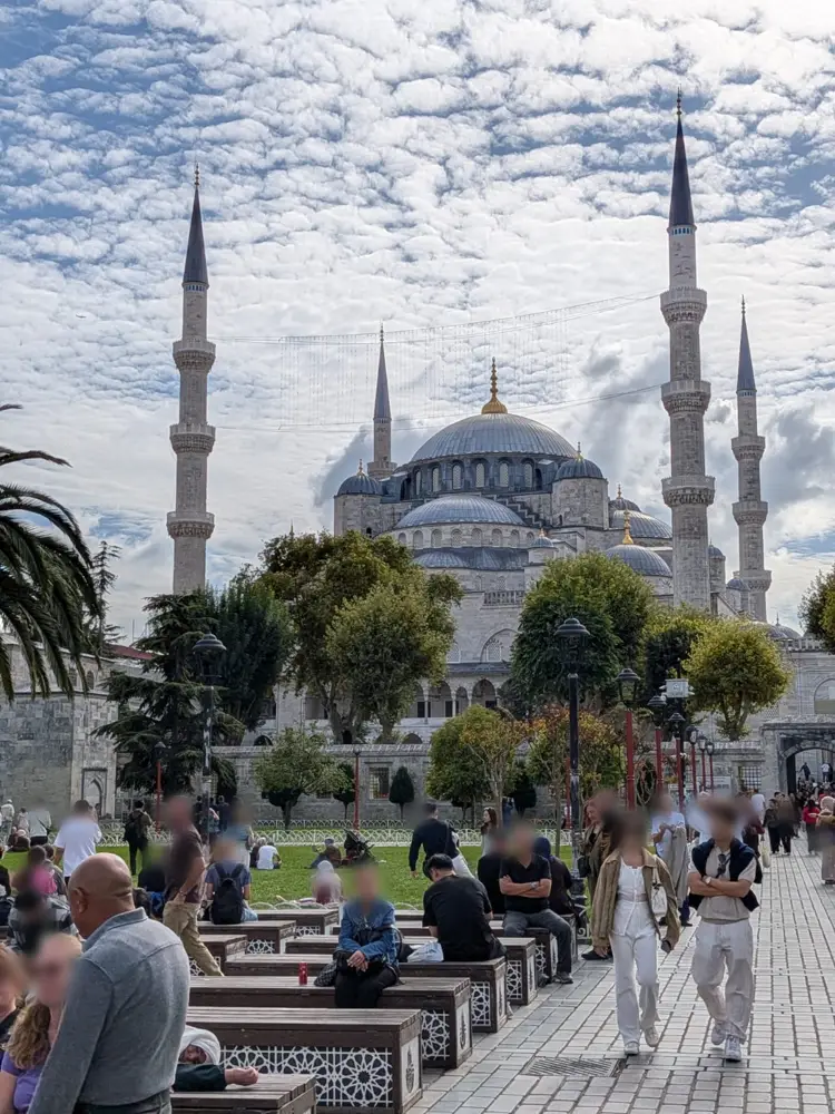 The Blue Mosque and its minarets rising above a busy square under a cloudy sky