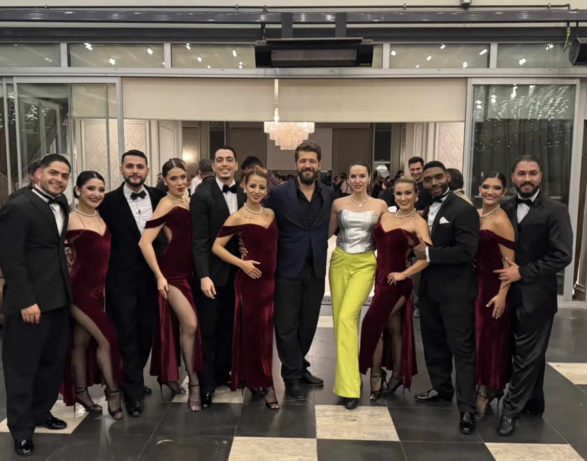 Emre Konuk and Anastasia Korneenko posing with the Che Tango dancers in tuxedos and burgundy velvet dresses